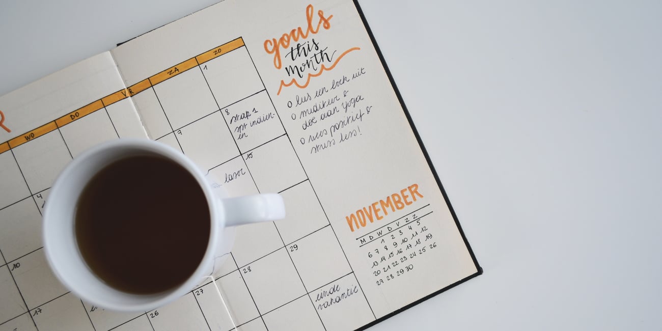 Coffee cup on top of calendar and goal list